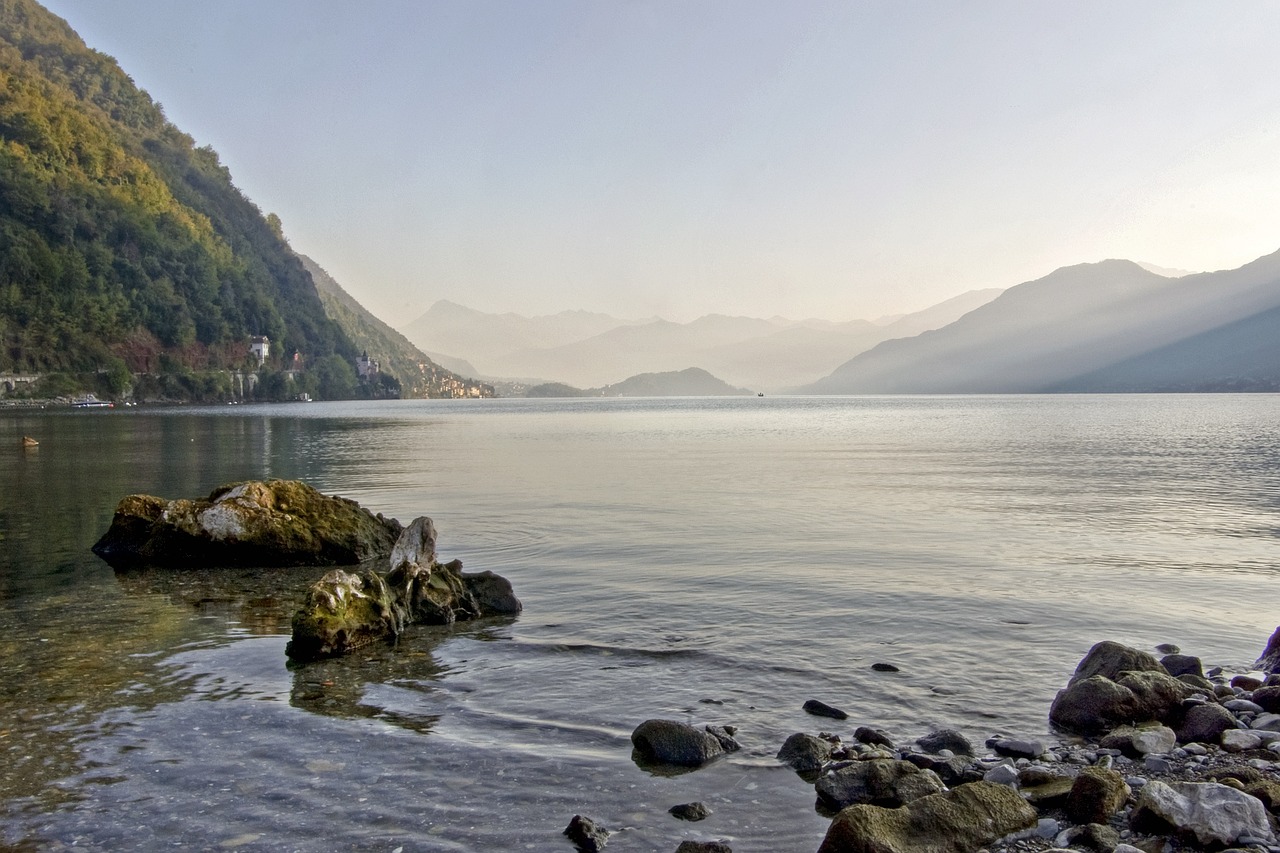 Kayak sul Lago di Como all'alba, con riflessi dorati sull'acqua e montagne sullo sfondo.