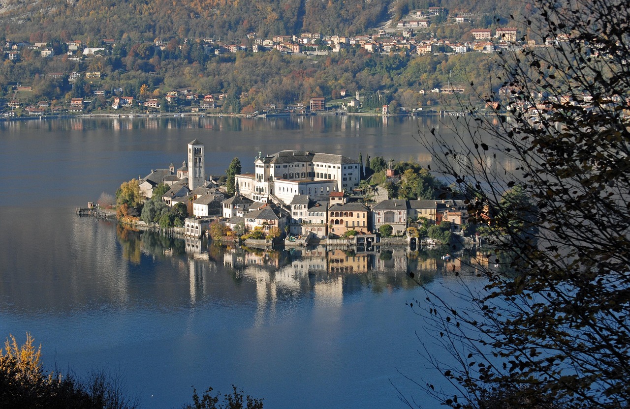 Panorama di un borgo lacustre tranquillo, circondato da acque serene e natura rigogliosa.