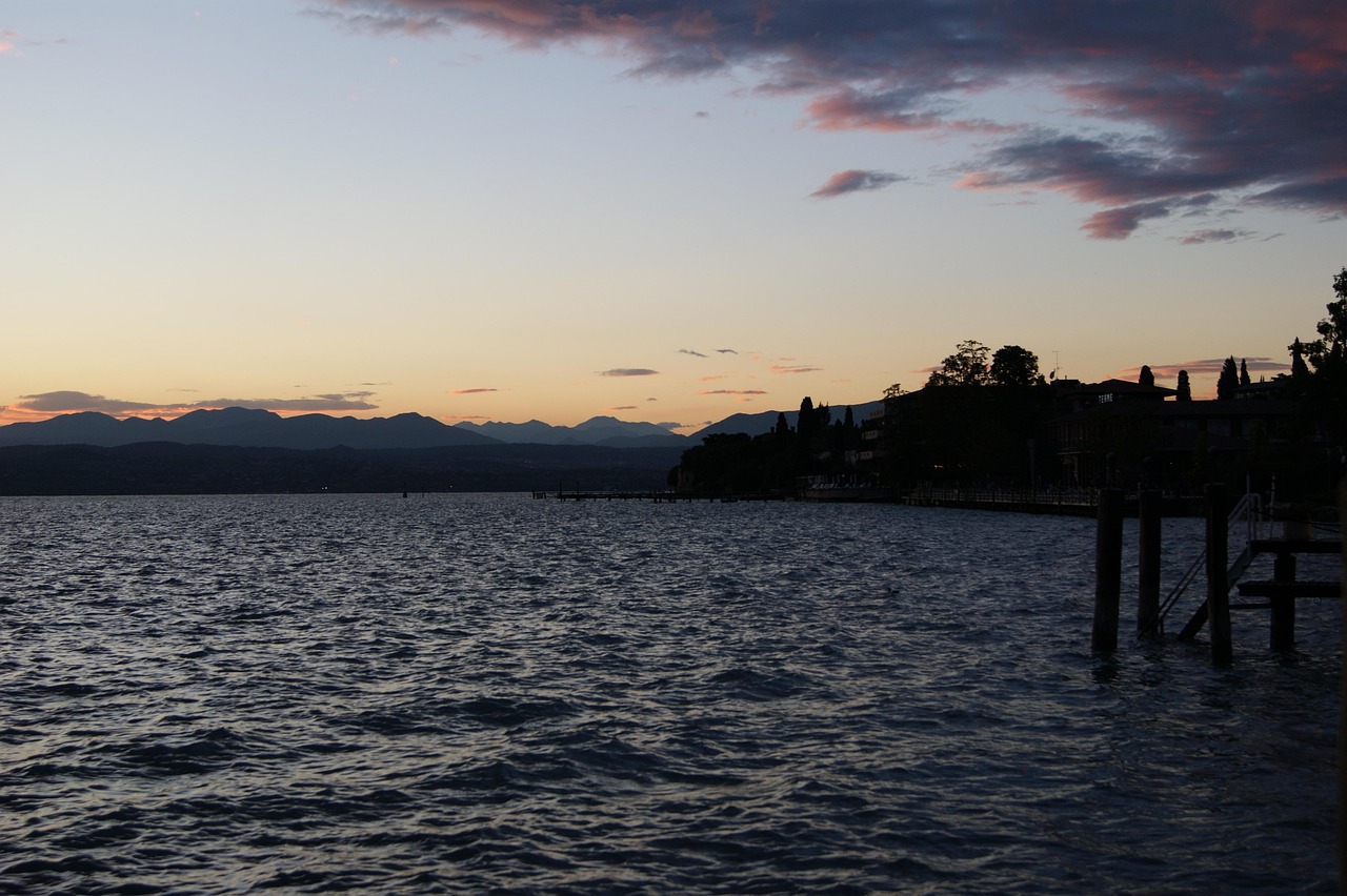 Vista panoramica dell'alba sul Lago Maggiore, con colori caldi che riflettono sull'acqua.