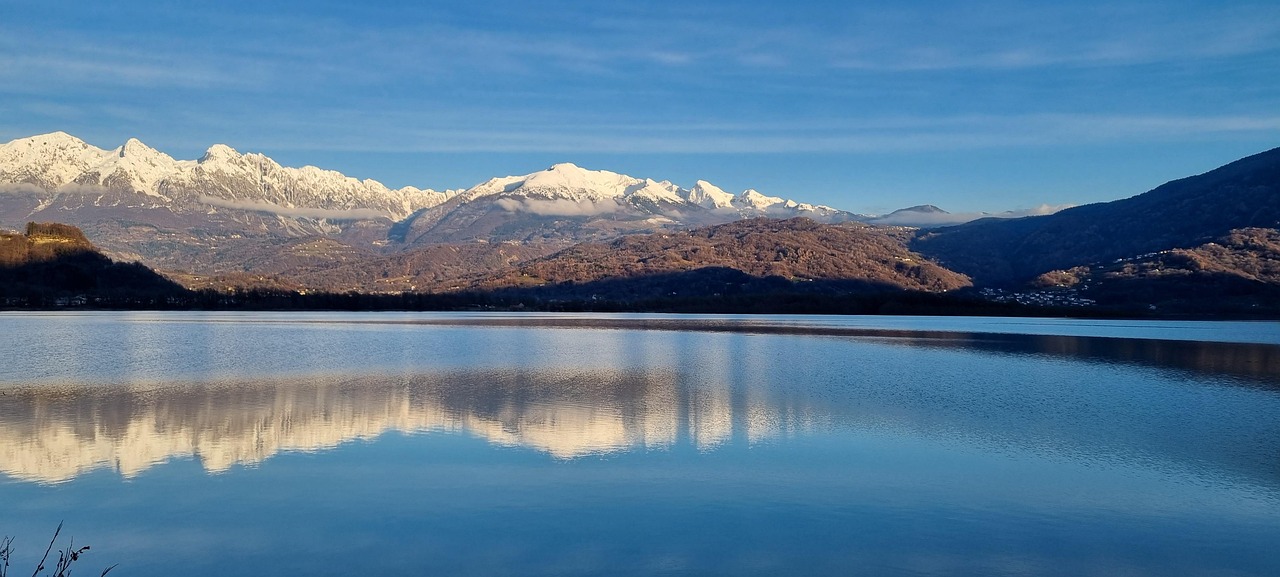 Vista panoramica delle Alpi lombarde, con cime maestose e cielo sereno.