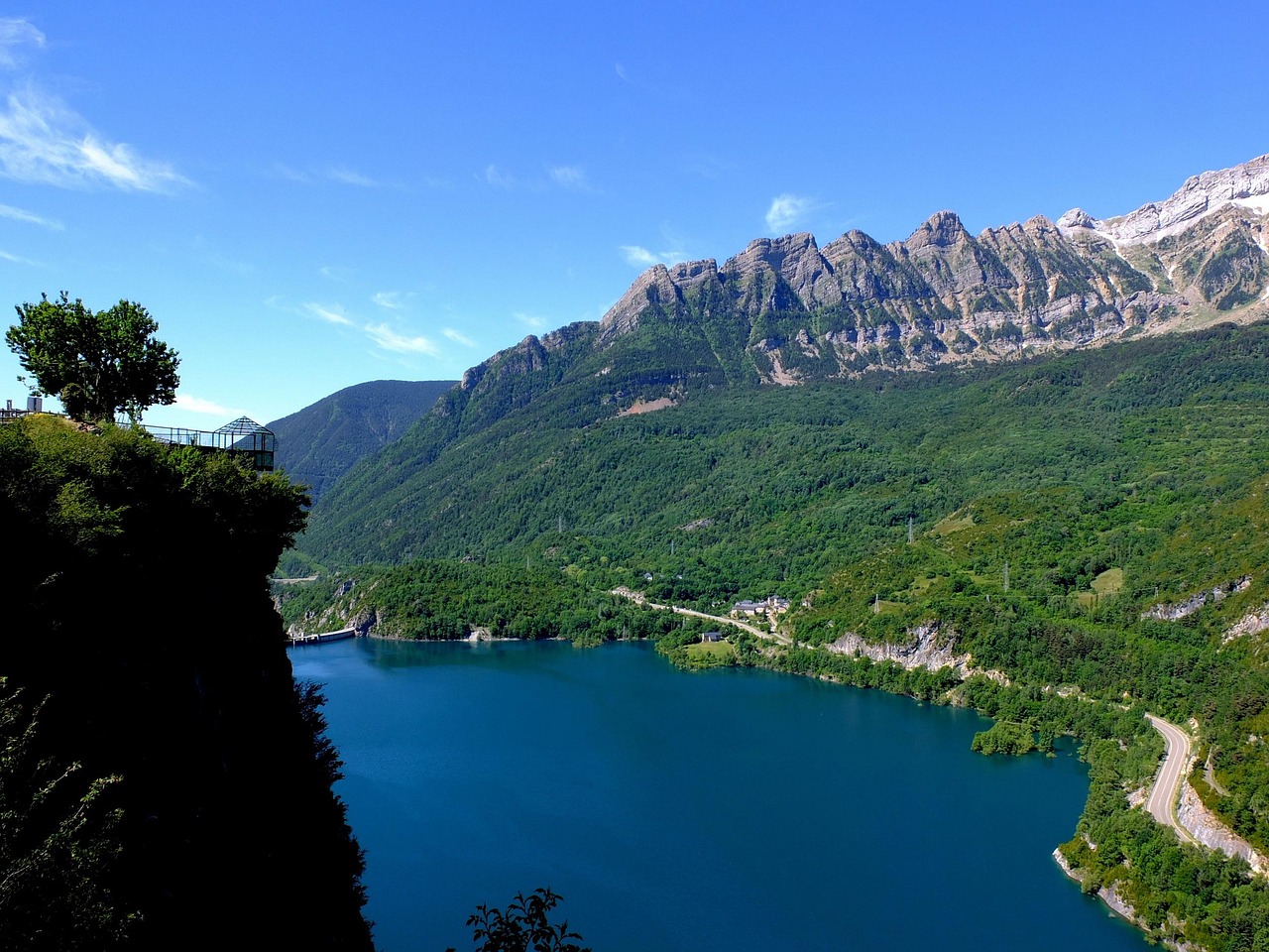 Vista panoramica dalla terrazza naturale del Resegone, con montagne e cielo blu sullo sfondo.