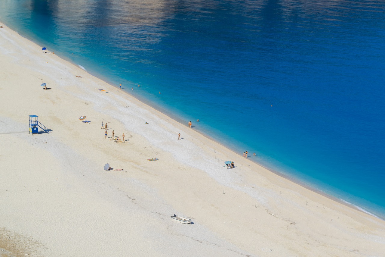 Spiaggia deserta a giugno, con sabbia bianca e mare cristallino, ideale per una fuga tranquilla.
