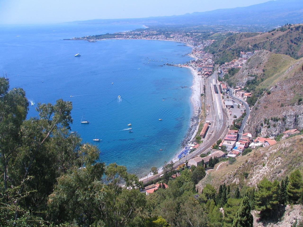 Spiaggia di sabbia dorata in Calabria, con mare cristallino e ombrelloni colorati.