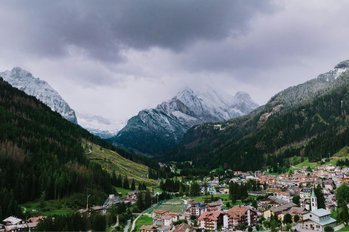 Borgo trentino innevato d'estate, con case tipiche circondate da paesaggi montani.