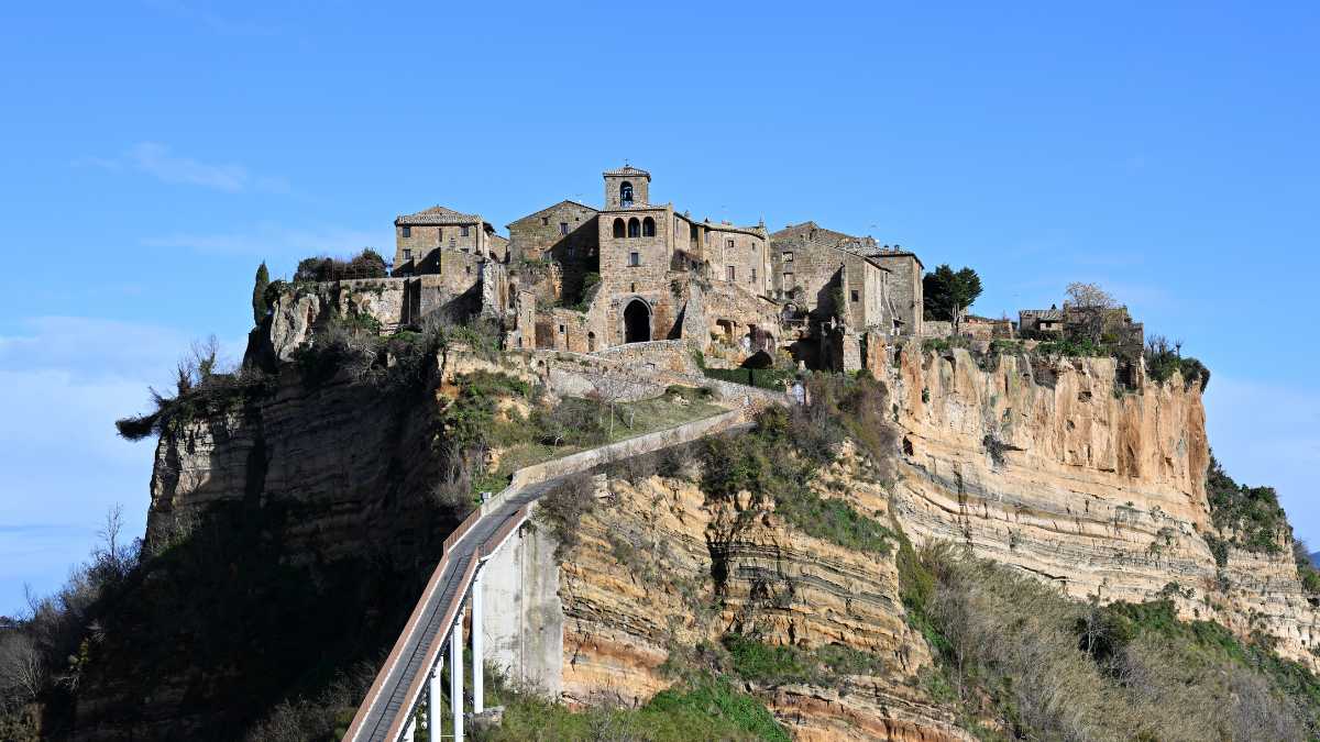Borgo medievale toscano visto dalla funicolare panoramica, circondato da colline verdi.