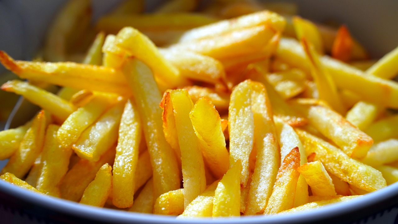 Friggitrice ad aria in cucina, con cibi fritti e un piatto di confronto accanto.