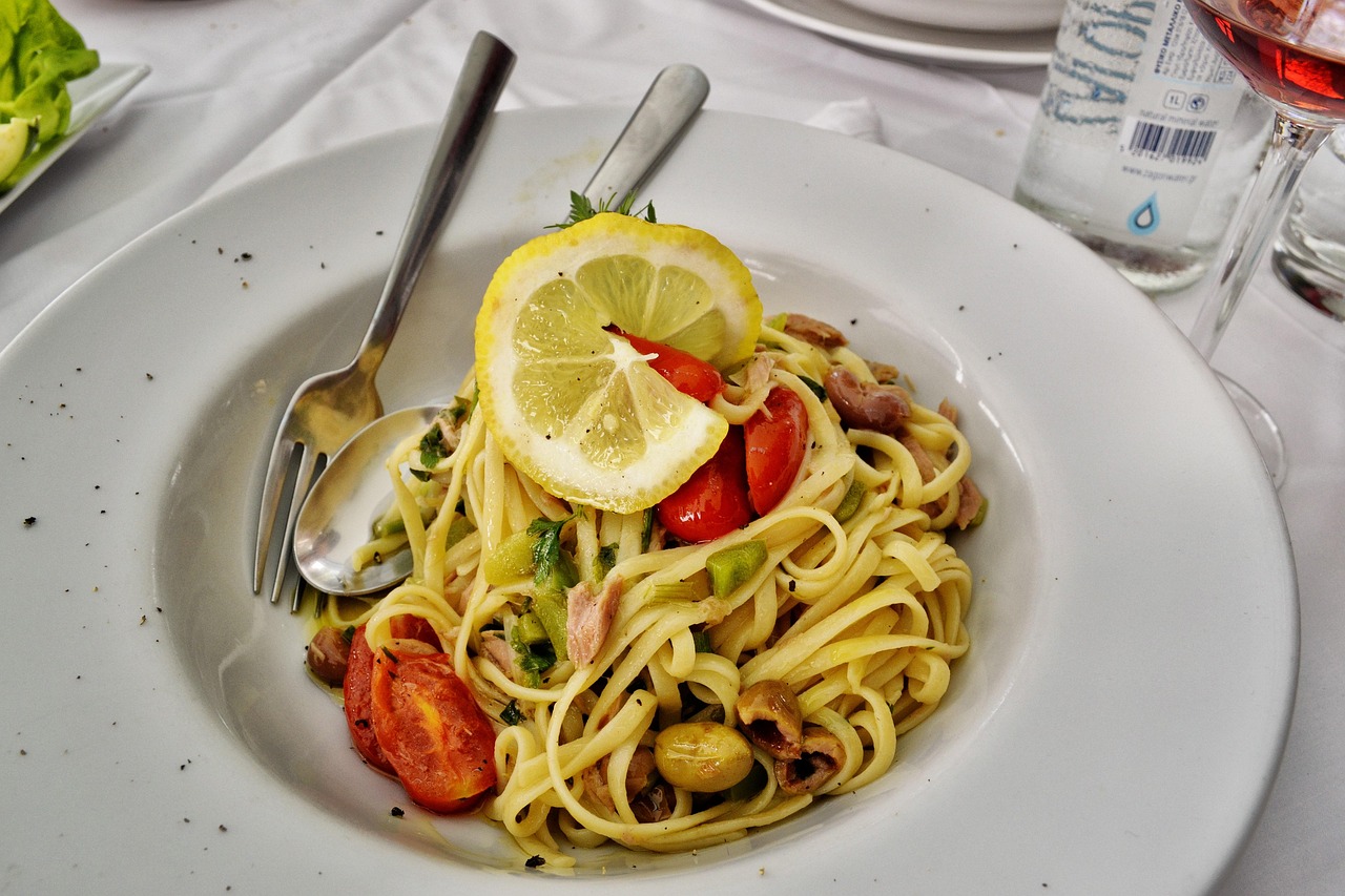 Spaghetti al tonno con tonno soffritto, piatto tipico degli anni '90, servito in un piatto bianco decorato.